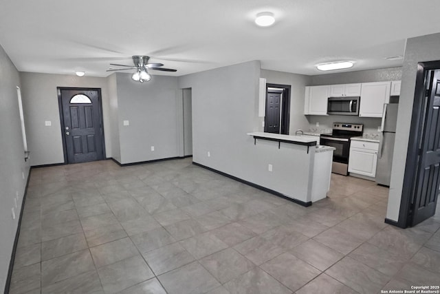 kitchen featuring a breakfast bar area, white cabinetry, kitchen peninsula, ceiling fan, and stainless steel appliances