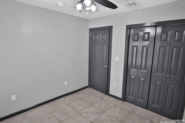 unfurnished bedroom with light tile patterned floors, ceiling fan, and a closet