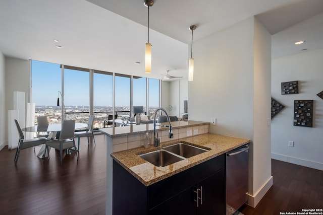 kitchen with sink, decorative light fixtures, light stone countertops, and kitchen peninsula