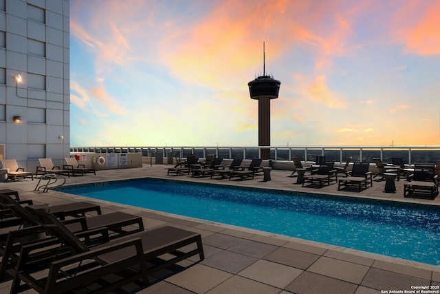 pool at dusk featuring a patio