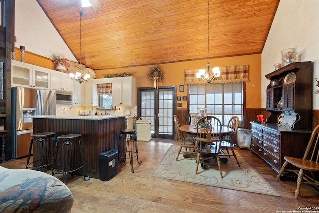 dining space with light hardwood / wood-style floors, high vaulted ceiling, wooden ceiling, and a notable chandelier