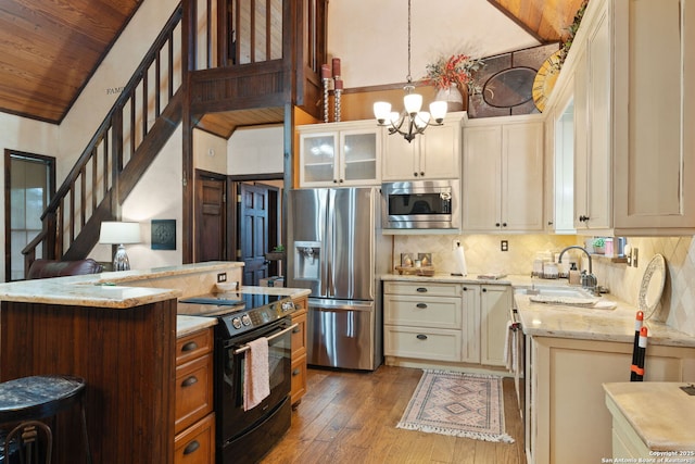 kitchen with sink, cream cabinetry, decorative light fixtures, stainless steel appliances, and tasteful backsplash