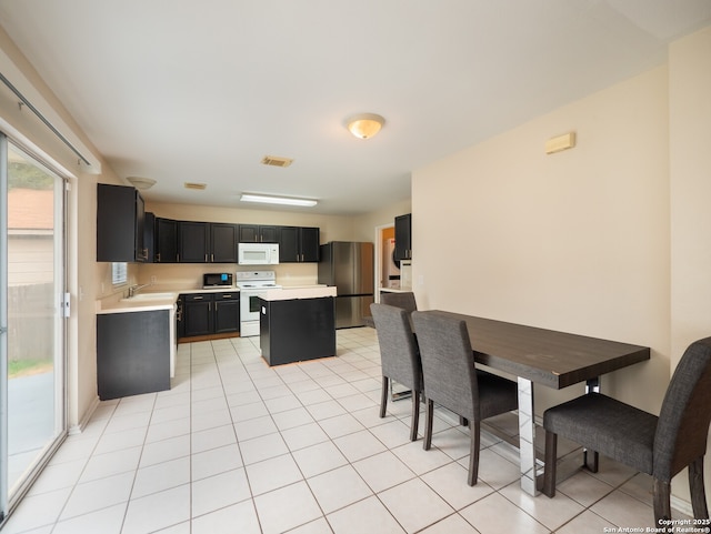 kitchen featuring white appliances, sink, a kitchen island, and light tile patterned floors