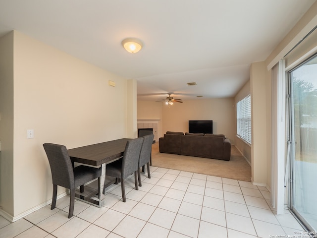 tiled dining area with ceiling fan and a tiled fireplace