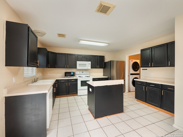 kitchen featuring stacked washing maching and dryer, a kitchen island, light tile patterned flooring, sink, and white appliances