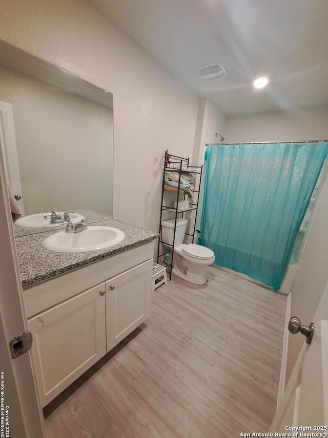 bathroom featuring toilet, hardwood / wood-style floors, vanity, and walk in shower