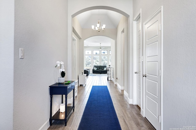 corridor with dark wood-type flooring and a chandelier