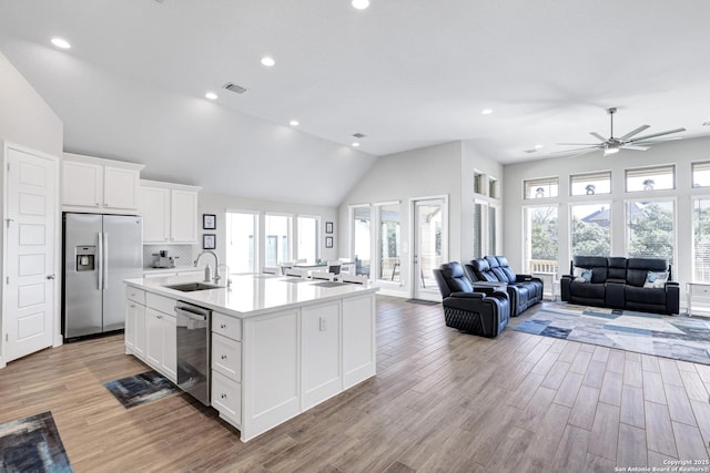 kitchen featuring sink, appliances with stainless steel finishes, an island with sink, light hardwood / wood-style floors, and white cabinets