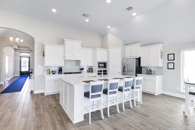 kitchen with an island with sink, white cabinets, light wood-type flooring, and black appliances