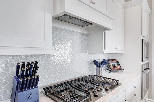 kitchen with white cabinetry, tasteful backsplash, custom range hood, and appliances with stainless steel finishes