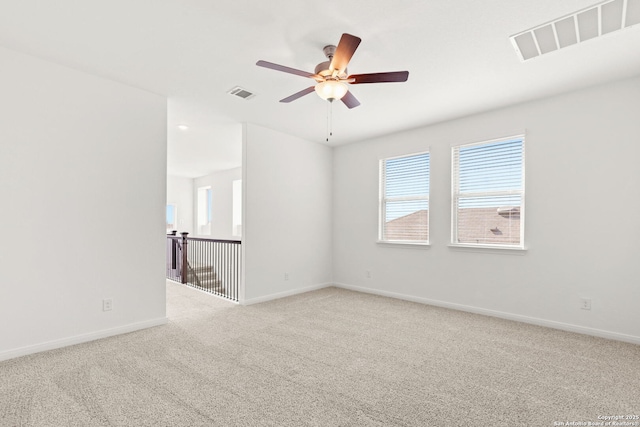 empty room with ceiling fan, light colored carpet, and a wealth of natural light