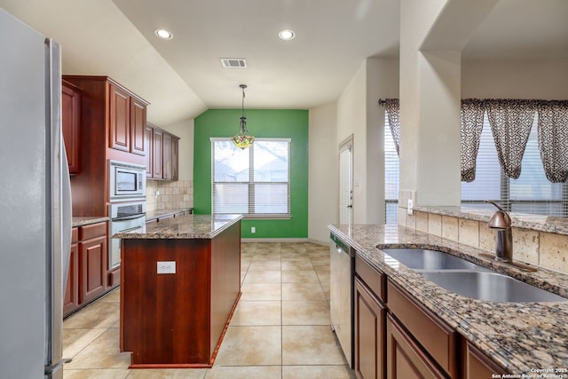 kitchen with stone countertops, sink, decorative backsplash, hanging light fixtures, and stainless steel appliances