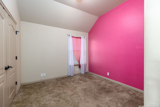 empty room featuring vaulted ceiling and carpet flooring