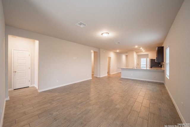 unfurnished living room featuring sink and light wood-type flooring