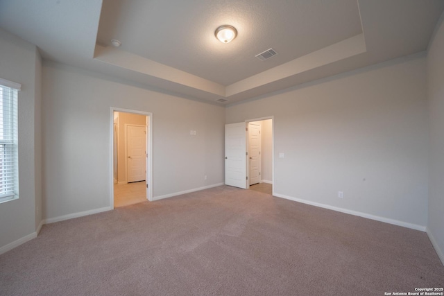 unfurnished bedroom with a raised ceiling and light carpet