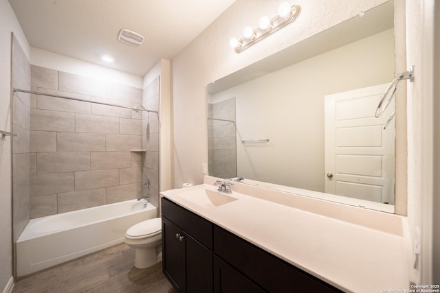 full bathroom featuring vanity, hardwood / wood-style floors, toilet, and tiled shower / bath