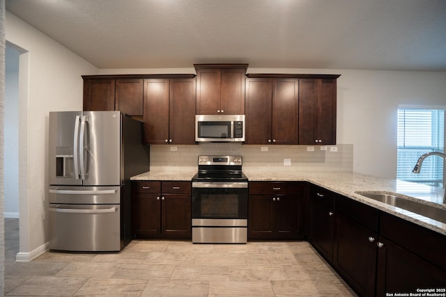 kitchen featuring tasteful backsplash, appliances with stainless steel finishes, dark brown cabinets, and light stone counters