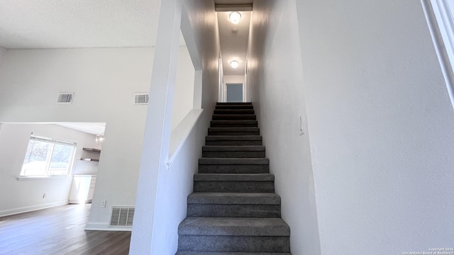 stairway with hardwood / wood-style flooring and a textured ceiling