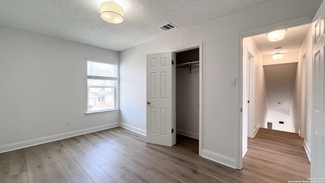 unfurnished bedroom featuring a closet, wood-type flooring, and a textured ceiling