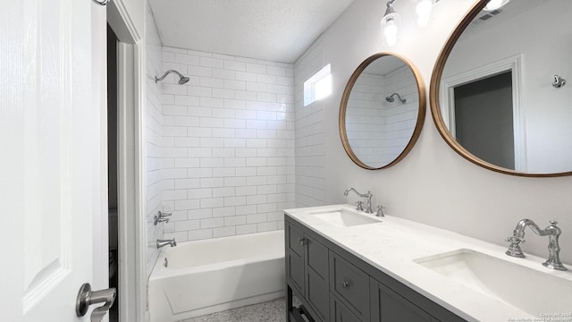 bathroom with vanity, tiled shower / bath, and a textured ceiling