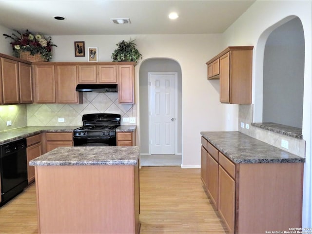 kitchen with a kitchen island, light hardwood / wood-style flooring, backsplash, and black appliances