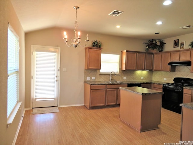 kitchen with black gas range oven, pendant lighting, sink, a center island, and light hardwood / wood-style floors