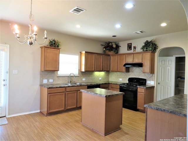 kitchen with sink, tasteful backsplash, a center island, light hardwood / wood-style flooring, and black appliances