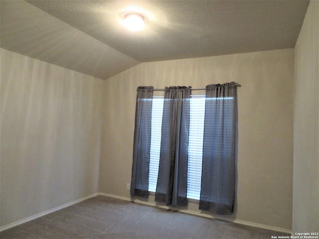 unfurnished room featuring vaulted ceiling, carpet floors, and a textured ceiling