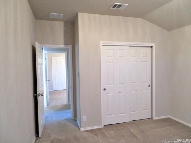 unfurnished bedroom featuring lofted ceiling, light colored carpet, and a closet