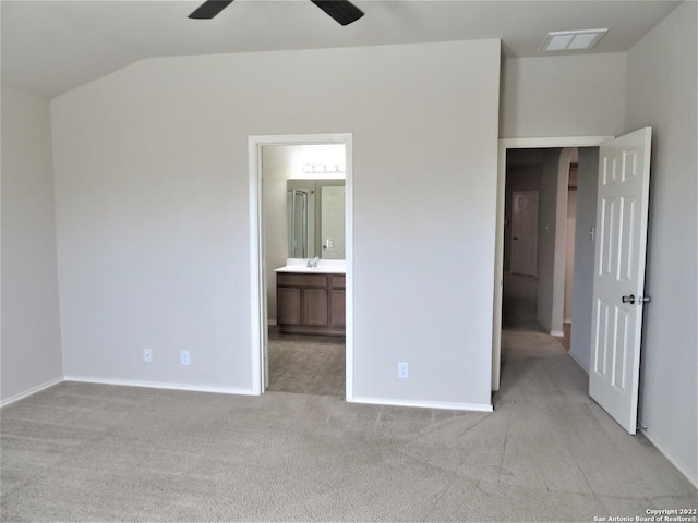 unfurnished bedroom featuring ceiling fan, light colored carpet, ensuite bathroom, and vaulted ceiling