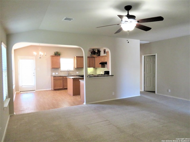 kitchen with tasteful backsplash, sink, vaulted ceiling, and light colored carpet