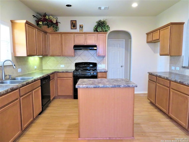 kitchen featuring sink, black appliances, a center island, and light wood-type flooring