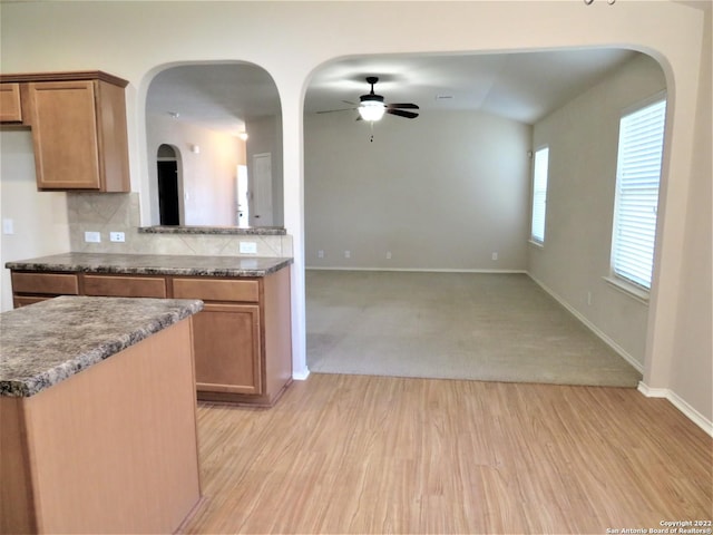 kitchen featuring lofted ceiling, backsplash, light hardwood / wood-style floors, and ceiling fan