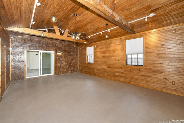 empty room with lofted ceiling with beams, wooden ceiling, concrete floors, and wood walls