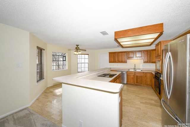 kitchen featuring sink, a textured ceiling, kitchen peninsula, ceiling fan, and black appliances