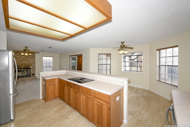 kitchen featuring black electric stovetop, a wealth of natural light, stainless steel fridge, and kitchen peninsula