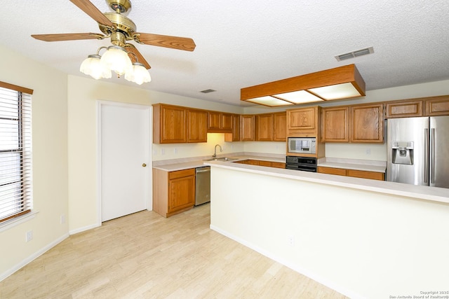 kitchen with stainless steel appliances, a healthy amount of sunlight, sink, and light hardwood / wood-style flooring