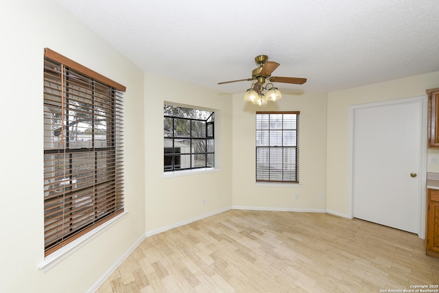 unfurnished room with ceiling fan, a textured ceiling, and light wood-type flooring