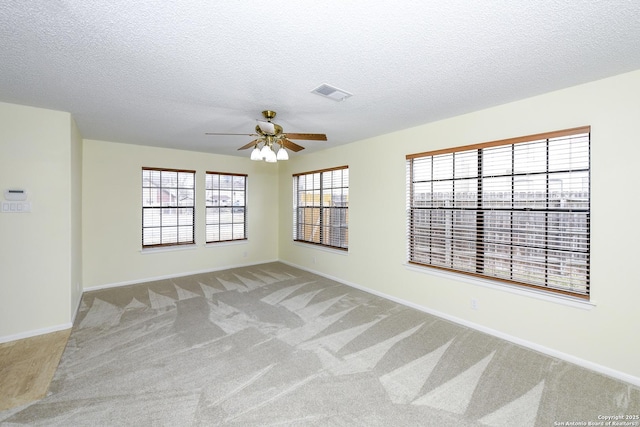 empty room featuring ceiling fan, light colored carpet, and a textured ceiling