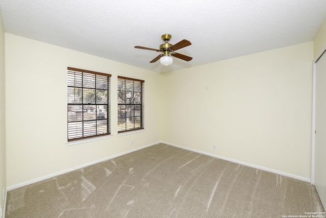 carpeted empty room with ceiling fan and a textured ceiling