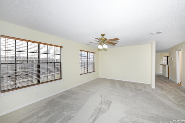 empty room featuring ceiling fan, light carpet, and a textured ceiling