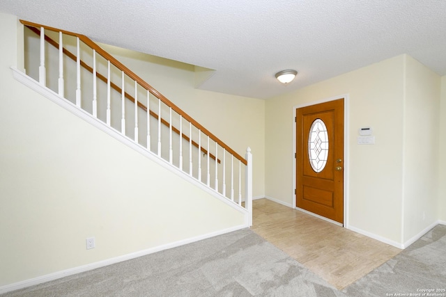 carpeted foyer featuring a textured ceiling