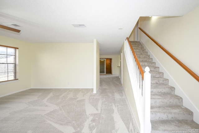 stairs featuring carpet floors and a textured ceiling