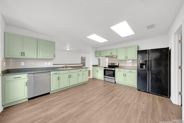 kitchen with green cabinetry, stainless steel appliances, light hardwood / wood-style floors, and sink