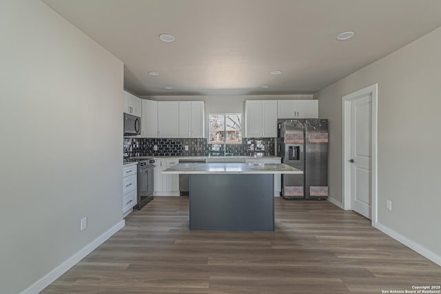 kitchen featuring white cabinets, backsplash, a center island, stainless steel appliances, and dark wood-type flooring