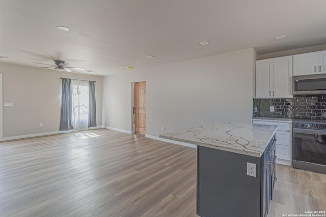 kitchen with white cabinetry, tasteful backsplash, a center island, stainless steel appliances, and light stone countertops