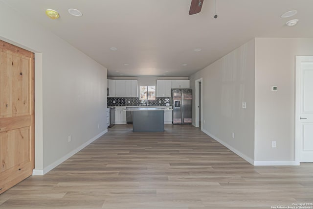 kitchen featuring light hardwood / wood-style flooring, white cabinetry, stainless steel refrigerator with ice dispenser, tasteful backsplash, and a kitchen island