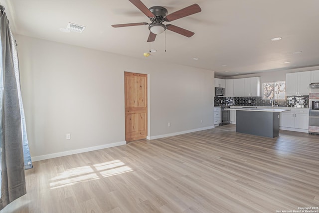 unfurnished living room with sink, ceiling fan, and light hardwood / wood-style flooring