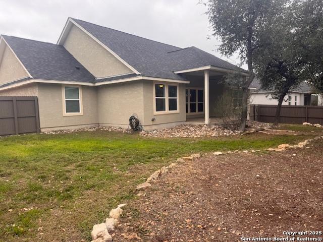 back of house with a patio and a lawn