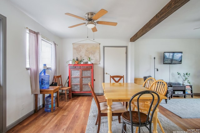 dining area with beamed ceiling, ceiling fan, and light wood-type flooring